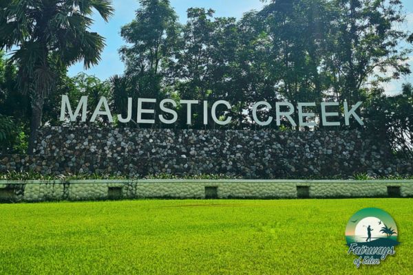 Entrance sign of Majestic Creek Country Club surrounded by greenery in Thailand